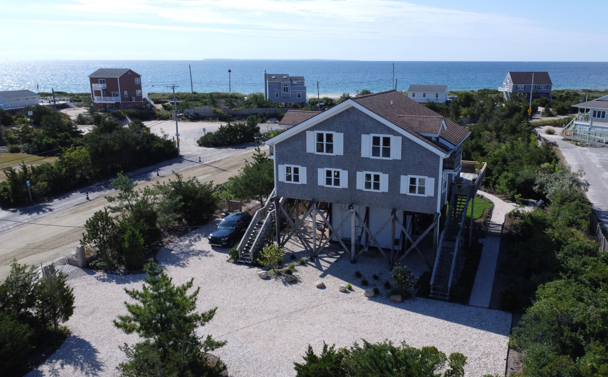 An aerial view of Surf House with the beach and ocean beyond.